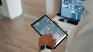 Hand tippt auf ein Tablet mit Kurschart und Orderbuch für die Eingabe einer Wertpapierorder